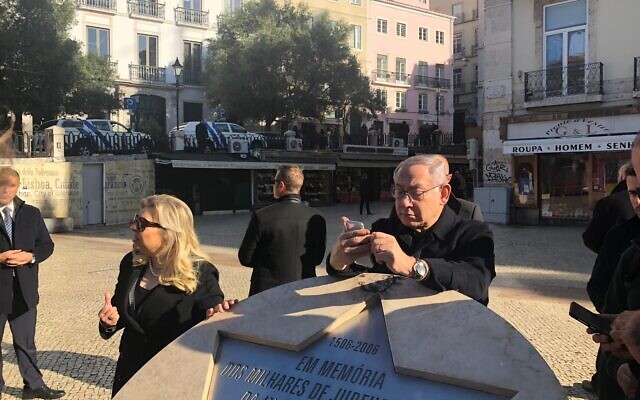 Le Premier ministre Benjamin Netanyahu consulte son téléphone en s'appuyant sur un mémorial d'un pogrom qui a fait des centaines de victimes juives à Lisbonne en 1506, le 5 décembre 2019. (Crédit : Shalom Yerushalmi/Zman Yisrael) Le Premier ministre Benjamin Netanyahu consulte son téléphone en s'appuyant sur un mémorial d'un pogrom qui a fait des centaines de victimes juives à Lisbonne en 1506, le 5 décembre 2019. (Crédit : Shalom Yerushalmi/Zman Yisrael)