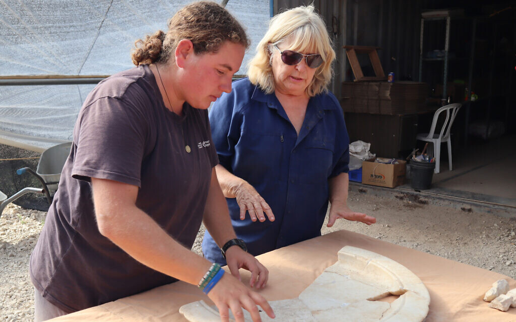L'archéologue de l'Autorité israélienne des antiquités Tali Erickson-Gini, (à droite), examine une plaque de marbre de la zone de l'autel de l'église byzantine découverte près d'Ashkelon. (Crédit : Anat Rasiuk, Israel Antiquities Authority)