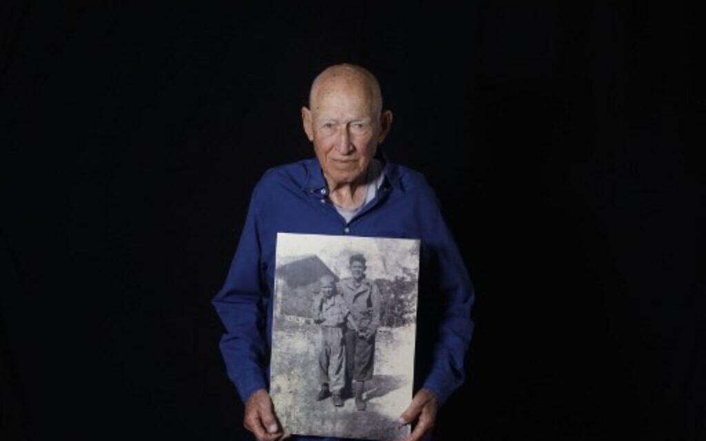 Le survivant de la Shoah Danny Chanoch, 87 ans, montre une photo de lui t de son frère Uri après la guerre, à son domicile de Karmei Yossef, le 10 décembre 2019. (Crédit : MENAHEM KAHANA / AFP)
