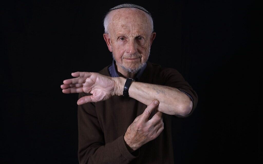 Le survivant de la Shoah Shaul Oren, montre sa matricule 125421, à son domicile de Jérusalem, le 2 décembre 2019. (Crédit : MENAHEM KAHANA / AFP)