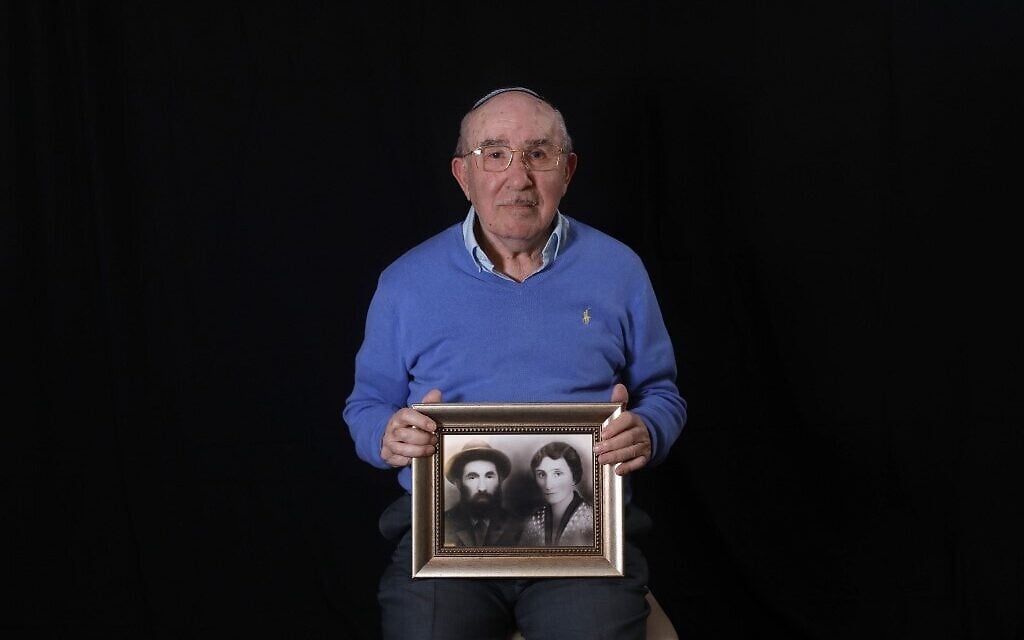 Le survivant de la Shoah Szmul Icek montre une photo de ses parents tués par les nazis, à son domicile de Jérusalem, le 8 décembre 2019. (Crédit : MENAHEM KAHANA / AFP)