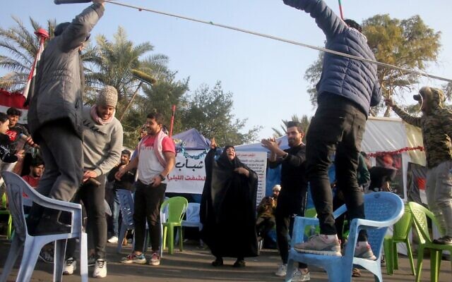 Des manifestants anti-gouvernementaux irakiens célèbrent devant leurs tentes sur la place Tahrir de Bagdad à la suite de la nouvelle du meurtre du commandant en chef des Gardiens de la révolution iraniens Qasem Soleimani. (Crédit : AFP) Des manifestants anti-gouvernementaux irakiens célèbrent devant leurs tentes sur la place Tahrir de Bagdad à la suite de la nouvelle du meurtre du commandant en chef des Gardiens de la révolution iraniens Qasem Soleimani. (Crédit : AFP)