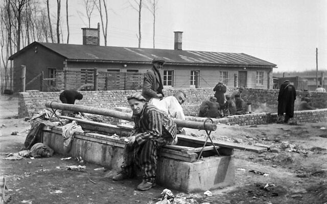 Sur cette photographie prise en avril 1945, des survivants du camp de concentration nazi de Buchenwald sont assis sur une latrine, après la libération du camp par les troupes alliées. (Crédit : Eric Schwab/AFP)