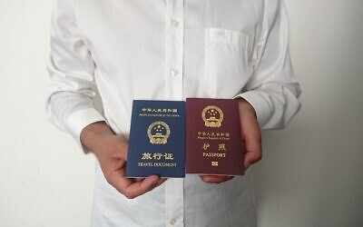 Sur une photo prise le 2 octobre 2019, on voit un homme ouïghour chinois non identifié dans la ville de Médine, tenant son passeport chinois expiré (rouge) et un document de voyage aller simple (bleu) délivré à sa place par la mission chinoise en Arabie Saoudite. (Crédit : AFP)