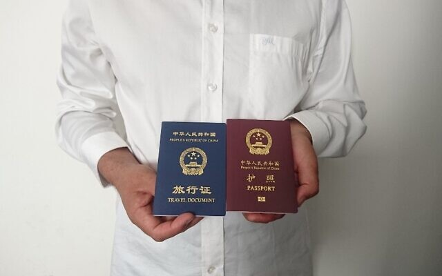 Sur une photo prise le 2 octobre 2019, on voit un homme ouïghour chinois non identifié dans la ville de Médine, tenant son passeport chinois expiré (rouge) et un document de voyage aller simple (bleu) délivré à sa place par la mission chinoise en Arabie Saoudite. (Crédit : AFP)