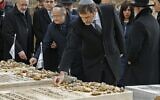 Le ministre français de l'Intérieur Christophe Castaner se rend sur les tombes des victimes de l'attentat de l'école Ozar Hatorah à Toulouse, au cimetière israélien de Givat Shaul à Jérusalem, le 23 janvier 2020. En arrière plan, Eva Sandler, qui a parti son mari et ses deux fils Aryeh et Gabriel lors de cette tuerie antisémite. (Crédit : JACK GUEZ / AFP)