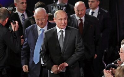 Le président israélien Reuven Rivlin escorte son homologue russe Vladimir Poutine à son siège lors du cinquième Forum mondial sur la Shoah au musée mémorial de la Shoah de Yad Vashem à Jérusalem, le 23 janvier 2020. Derrière eux se trouve Moshe Kantor du Forum. (Abir Sultan/POOL/AFP)