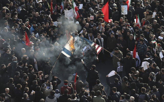 Des personnes en deuil brûlent les drapeaux des États-Unis et d'Israël lors d'une cérémonie funéraire sur la place Enqelab-e-Eslami (Révolution islamique) à Téhéran, en Iran, le 6 janvier 2020, pour le général iranien Qassem Soleimani et ses frères de combat, tués en Irak dans une frappe de drones américains vendredi. (Crédit : AP Photo / Ebrahim Noroozi)