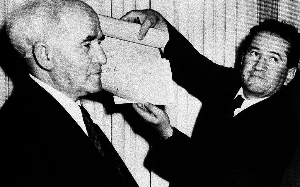 Un officiel montre le document signé qui proclame l'établissement du nouvel État juif d'Israël déclaré par le premier ministre David Ben Gourion, à gauche, à Tel Aviv à minuit le 14 mai 1948. (Crédit : Photo AP)