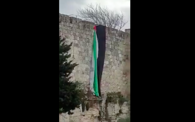 Capture d'écran d'une vidéo montrant le retrait d'un drapeau géant des murs de la Vieille Ville de Jérusalem. (Crédit : Twitter) Capture d'écran d'une vidéo montrant le retrait d'un drapeau géant des murs de la Vieille Ville de Jérusalem. (Crédit : Twitter)