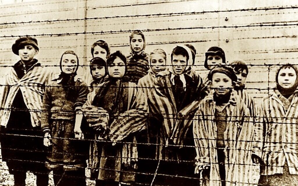 Un groupe d'enfants portant des uniformes de camp de concentration derrière une clôture de barbelés dans le camp de concentration nazi d'Oswiecim (Auschwitz), photographié juste après la libération par l'armée soviétique, en janvier 1945. (AP Photo/ File)