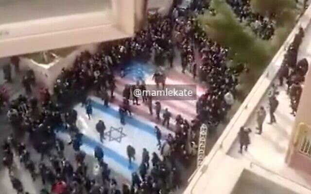 Capture d'écran d'une vidéo montrant apparemment des manifestants anti-régime iraniens refusant de marcher sur les drapeaux américain et israélien lors d'une manifestation dans une université de Téhéran, le 12 janvier 2020. (Twitter) Capture d'écran d'une vidéo montrant apparemment des manifestants anti-régime iraniens refusant de marcher sur les drapeaux américain et israélien lors d'une manifestation dans une université de Téhéran, le 12 janvier 2020. (Twitter)