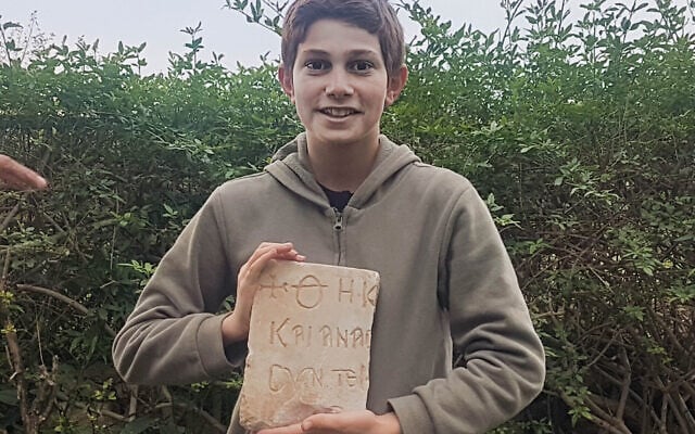 Stav Meir, 13 ans, tenant une inscription funéraire grecque de 1500 ans qu'il a découverte près de Césarée. (Karem Said/ Autorité des antiquités d'Israël)