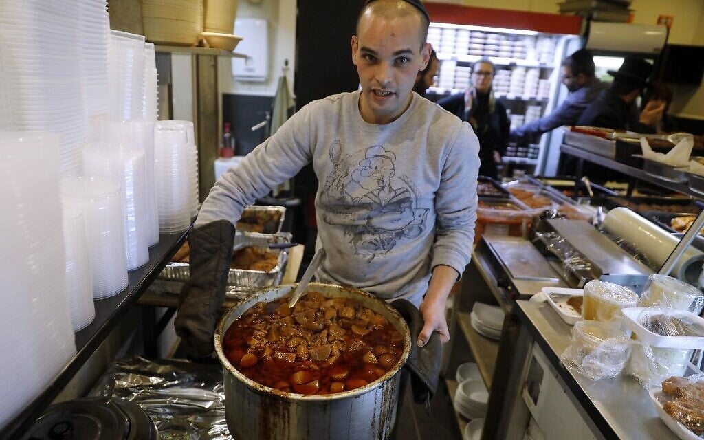 Un Israélien tient une casserole de 'Hamin, un ragoût traditionnel de la cuisine juive, au restaurant Maadaniyat Shef, à Bnei Brak le 16 janvier 2020. (Crédit : MENAHEM KAHANA / AFP) Un Israélien tient une casserole de 'Hamin, un ragoût traditionnel de la cuisine juive, au restaurant Maadaniyat Shef, à Bnei Brak le 16 janvier 2020. (Crédit : MENAHEM KAHANA / AFP)