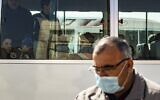 Un passager porte un masque par mesure de précaution contre le coronavirus à son arrivée en bus dans la zone kurde syrienne en provenance du Kurdistan irakien via le poste frontière de Semalka au nord-est de la Syrie le 26 février 2020. (Crédit : Delil SOULEIMAN / AFP)