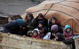 Des Syriens à l'arrière d'un camion fuient l'avancée des forces gouvernementales dans la province d'Idlib, en Syrie, vers la frontière turque, le 30 janvier 2020 (Crédit : Ghaith Alsayed/AP)