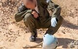 Un aviateur inspecte le casque d'un pilote israélien mort dans un accident d'avion dans le sud d'Israël en 1984, dans le désert de Paran en février 2020. (Crédit : armée israélienne)