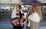 Une membre des Femmes du mur aide une femme à poser un tefillin à la gare Savidor de Tel Aviv, le 17 février 2020 (Autorisation : Femmes du mur)