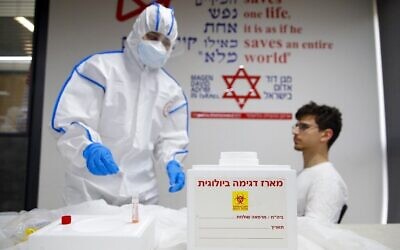 Illustration : Un ambulancier du Magen David Adom effectue un test de coronavirus sur un bénévole au centre national d'opérations du coronavirus à Kiryat Ono, le 26 février 2020. (Crédit : Jack Guez/AFP)