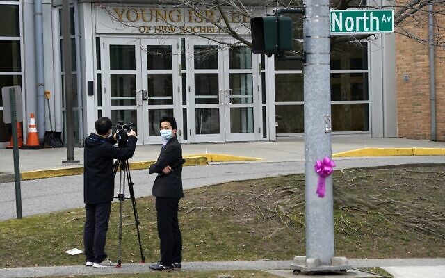 Des médias portant un masque de protection devant la synagogue Young Israel of New Rochelle, à New York, le 10 mars 2020, au centre d'une épidémie dans le comté de Westchester (Crédit : TIMOTHY A. CLARY / AFP)