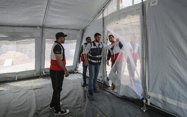 Des membres du ministère palestinien de la Santé, en partenariat avec l'Organisation mondiale de la santé (OMS), installent des tentes extérieures pour un examen médical préliminaire des patients suspectés d’être porteurs du coronavirus au poste-frontière de Rafah avec l'Égypte, dans le sud de la bande de Gaza, le 12 mars 2020. (Crédit : SAID KHATIB / AFP) Des membres du ministère palestinien de la Santé, en partenariat avec l'Organisation mondiale de la santé (OMS), installent des tentes extérieures pour un examen médical préliminaire des patients suspectés d’être porteurs du coronavirus au poste-frontière de Rafah avec l'Égypte, dans le sud de la bande de Gaza, le 12 mars 2020. (Crédit : SAID KHATIB / AFP)