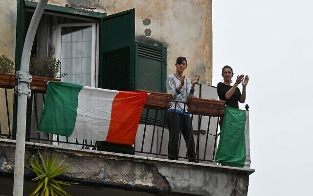 Des gens tapent dans leurs mains dans le cadre du flash mob "Un applauso per l'Italia" (Applaudissement pour l'Italie) dans le quartier Garbatella de Rome, le 14 mars 2020, lors de l'épidémie de Covid-19. (Crédit : Andreas SOLARO / AFP)