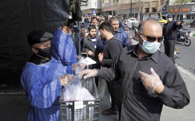 Des personnes font la queue pour recevoir des paquets pour lutter contre la coronavirus COVID-19 fournis pa le Basijj, une milice loyale aux autorités de la République islamique d'Iran, dans des stands devant la station de métro Meydane Valiasr dans la capitale Téhéran le 15 mars 2020. - (Photo par STRINGER / AFP) Des personnes font la queue pour recevoir des paquets pour lutter contre la coronavirus COVID-19 fournis pa le Basijj, une milice loyale aux autorités de la République islamique d'Iran, dans des stands devant la station de métro Meydane Valiasr dans la capitale Téhéran le 15 mars 2020. - (Photo par STRINGER / AFP)