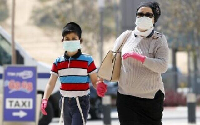 Des personnes portant des masques de protection entrent au Samson Assuta Ashdod University Hospital, le 16 mars 2020 dans la ville d'Ashdod, au sud d'Israël (JACK GUEZ / AFP)