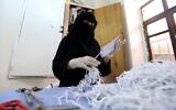 Une femme yéménite fabrique des masques dans une usine textile de la capitale Sanaa, le 16 mars 2020, en pleine pandémie de coronavirus. (Crédit :  Mohammed HUWAIS / AFP)