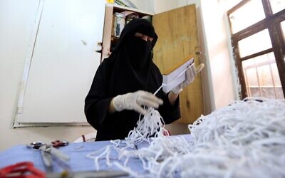 Une femme yéménite fabrique des masques dans une usine textile de la capitale Sanaa, le 16 mars 2020, en pleine pandémie de coronavirus. (Crédit :  Mohammed HUWAIS / AFP)