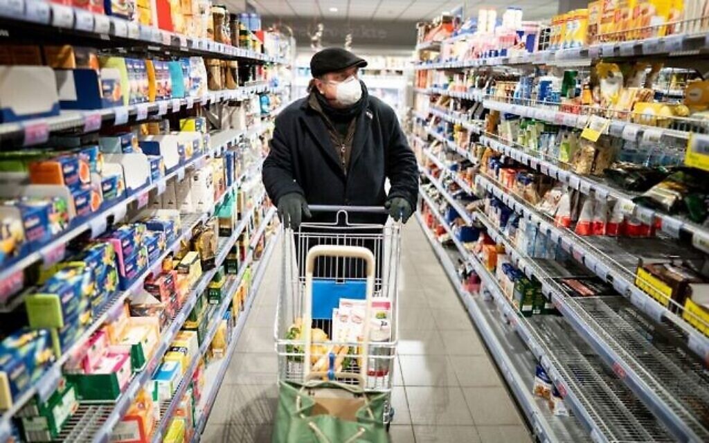 Un homme portant un masque facial, porté par beaucoup comme mesure de protection contre le nouveau coronavirus COVID-19, pousse un caddie dans un supermarché de Berlin le 17 mars 2020. (Kay Nietfeld / dpa / AFP)