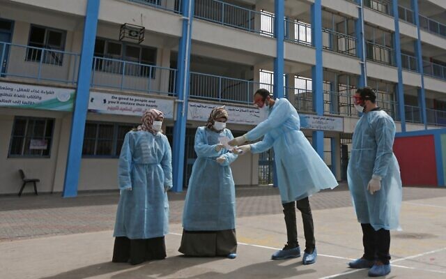 Des soignants palestiniens portent des masques de protection et se préparent à soigner et isoler des patients du coronavirus, dans la cour d'une école de l'UNRWA, à Gaza, le 18 mars 2020. (Crédit : MAHMUD HAMS / AFP)