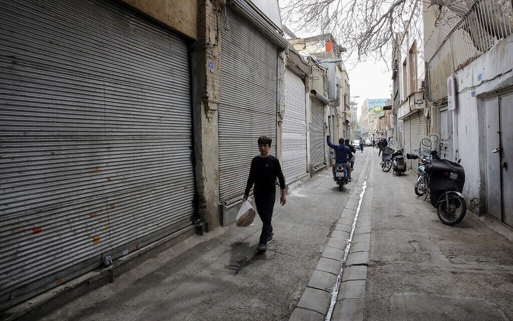 Des jeunes iraniens passent à côté de boutiques fermées dans le grand bazaar de la capitale Téhéran pendant la crise du coronavirus, le 18 mars 2020. (Photo par - / AFP) Des jeunes iraniens passent à côté de boutiques fermées dans le grand bazaar de la capitale Téhéran pendant la crise du coronavirus, le 18 mars 2020. (Photo par - / AFP)