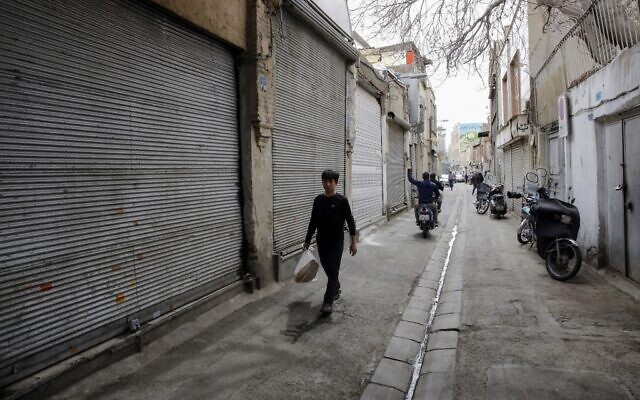 Des jeunes iraniens passent à côté de boutiques fermées dans le grand bazaar de la capitale Téhéran pendant la crise du coronavirus, le 18 mars 2020. (Photo par - / AFP)