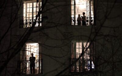 Des Parisiens applaudissent les travailleurs de santé depuis leur balcon à 20h, à Paris, le 18 mars 2020. (Crédit : THOMAS COEX / AFP)