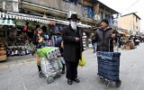 Un juif ultra-orthodoxe portant un masque au marché Mahane Yehuda de Jérusalem, le 19 mars 2020. (Crédit : EMMANUEL DUNAND / AFP)