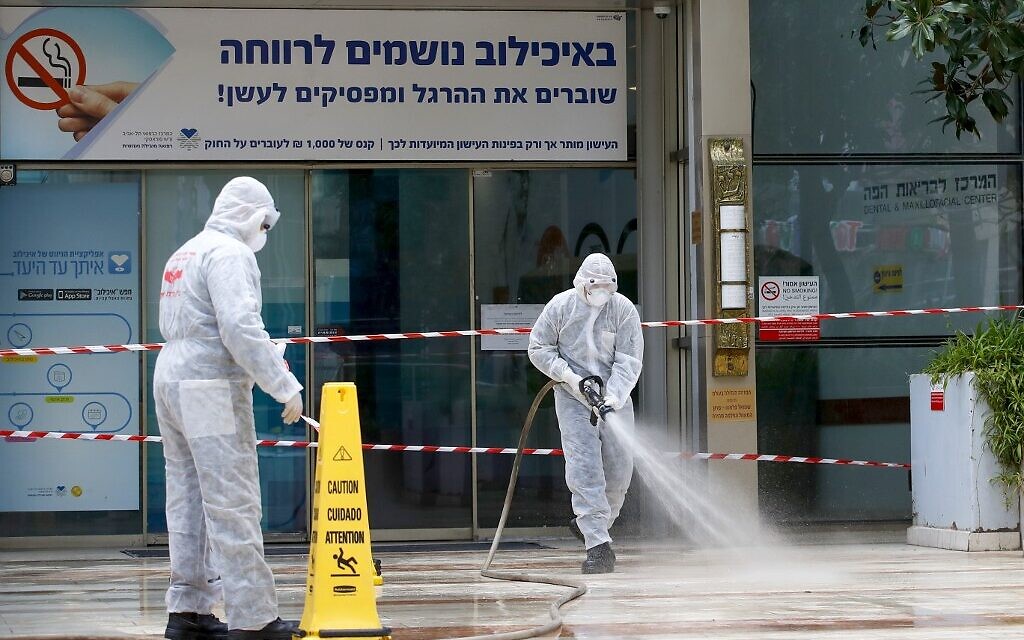 Un pompier israélien pulvérise du désinfectant à l'entrée du centre médical Sourasky de Tel-Aviv, le 20 mars 2020. (Crédit : JACK GUEZ / AFP)