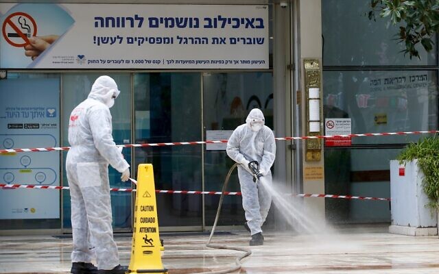 Un pompier israélien pulvérise du désinfectant à l'entrée du centre médical Sourasky de Tel-Aviv, le 20 mars 2020. (Crédit : JACK GUEZ / AFP)