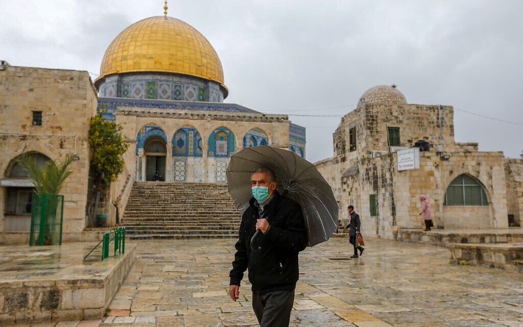 Un Palestinien portant un masque de protection contre le COVID-19, se trouve devant la mosquée du Dôme du Rocher dans l'enceinte presque déserte de la mosquée Al-Aqsa, dans la vieille ville de Jérusalem, le 20 mars 2020. (Crédit : AHMAD GHARABLI / AFP)