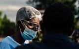 Un membre de l'hôpital Parirenyatwa Hospita contrôle les personnes et leur donne du désinfectant pour les mains avant qu'elles entrent dans l'hôpital alors que le pays tente de bloquer la propagation du coronavirus COVID-19 à Harare au Zimbabwe, le 23 mars 2020. (Photo par Jekesai NJIKIZANA / AFP)