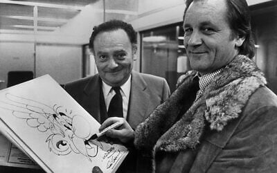 Sur cette photo prise dans les années 1970, les artistes français de bande dessinée Albert Uderzo (à droite) et René Goscinny (à gauche) posent avec un dessin de leur personnage Astérix. Uderzo est décédé à l'âge de 92 ans le 24 mars 2020, a annoncé sa famille. (Crédit : Staff / AFP)