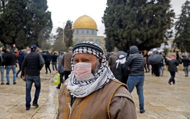 Un Palestinien portant un masque de protection comme mesure de protection contre le coronavirus se tient devant la mosquée du Dôme du Rocher sur le mont du Temple, dans la vieille ville de Jérusalem, avant les prières du vendredi, le 6 mars 2020. (Crédit : Ahmad Gharabli / AFP) Un Palestinien portant un masque de protection comme mesure de protection contre le coronavirus se tient devant la mosquée du Dôme du Rocher sur le mont du Temple, dans la vieille ville de Jérusalem, avant les prières du vendredi, le 6 mars 2020. (Crédit : Ahmad Gharabli / AFP)