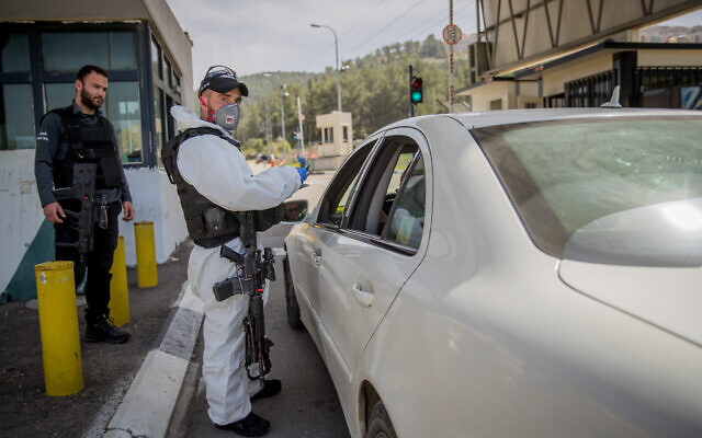 Un membre de la police des frontières israélienne porte un équipement de protection et un masque contre le coronavirus, au point de contrôle d'Ein Yael, près du zoo biblique de Jérusalem, le 11 mars 2020. (Crédit : Yonatan Sindel / Flash90) Un membre de la police des frontières israélienne porte un équipement de protection et un masque contre le coronavirus, au point de contrôle d'Ein Yael, près du zoo biblique de Jérusalem, le 11 mars 2020. (Crédit : Yonatan Sindel / Flash90)