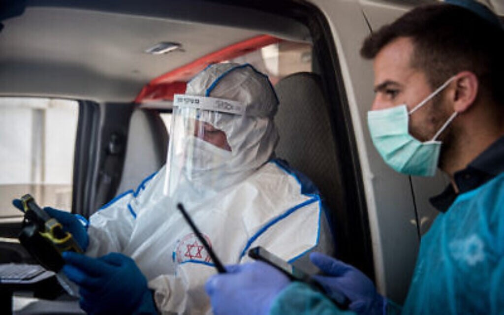 Des ambulanciers du service d’urgence du Magen David Adom portant des vêtements de protection à titre préventif contre le coronavirus conduisent une femme soupçonnée d’être porteuse du coronavirus au centre médical Shaare Zedek de Jérusalem, le 24 mars 2020. (Crédit : Yonatan Sindel / Flash90)
