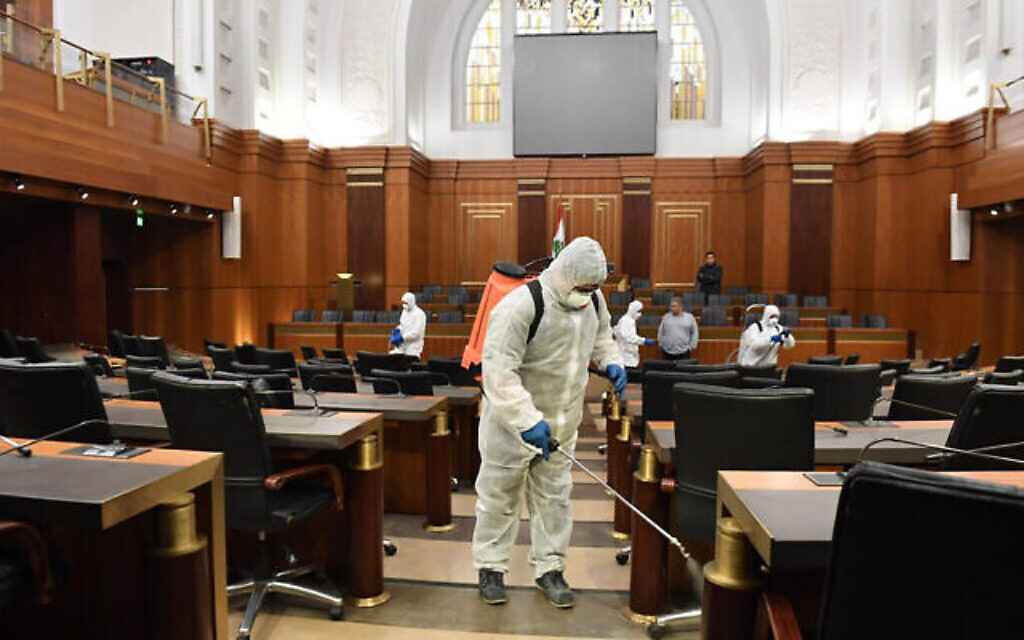 Des agent en tenue de protection désinfectent par précaution le hall principal du Parlement libanais, à Beyrouth, le 10 mars 2020. (Crédit : AP Photo / Ali Fawaz, Bureau médiatique du Parlement libanais)