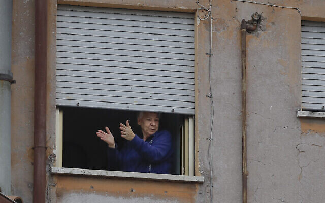 Une femme applaudit depuis sa fenêtre dans le quartier Garbatella de Rome, le 14 mars 2020. (Crédit : AP Photo/Alessandra Tarantino)