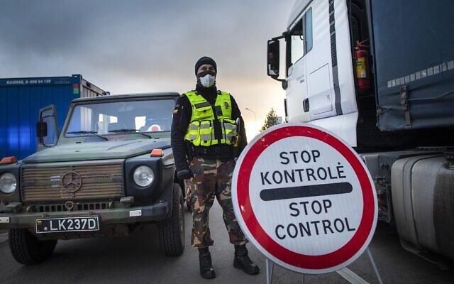 Illustration : Un garde-frontière lituanien se tient à côté de camions bloqués dans les embouteillages sur 60 kilomètres à la frontière lituanienne pour entrer en Pologne, le mardi 17 mars 2020. (AP Photo/Mindaugas Kulbis)