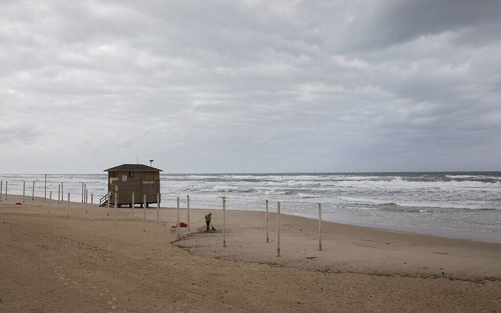 Un homme nettoie une plage vide de Bat Yam, le 18 mars 2020, en pleine pandémie de coronavirus. (Crédit : AP Photo/Sebastian Scheiner) Un homme nettoie une plage vide de Bat Yam, le 18 mars 2020, en pleine pandémie de coronavirus. (Crédit : AP Photo/Sebastian Scheiner)