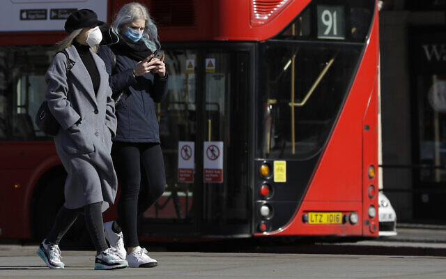 Deux femmes portent des masques de protection en pleine pandémie de coronavirus, à Londres, le 22 mars 2020. (Crédit : AP Photo/Kirsty Wigglesworth) Deux femmes portent des masques de protection en pleine pandémie de coronavirus, à Londres, le 22 mars 2020. (Crédit : AP Photo/Kirsty Wigglesworth)