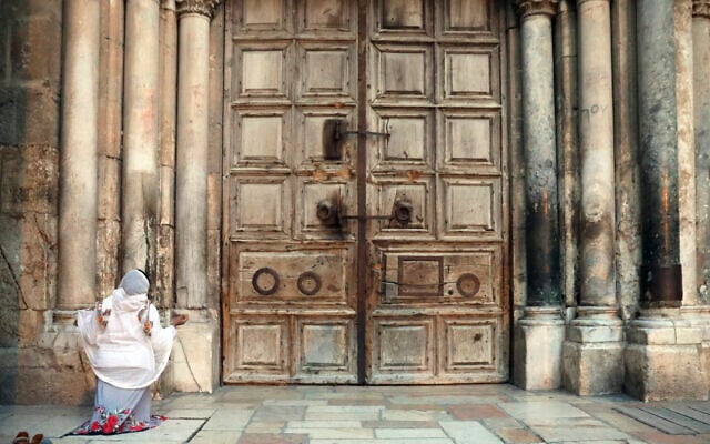 Une femme prie devant l'église fermée du Saint-Sépulcre, dans la Vieille Ville de Jérusalem, le 25 mars 2020. (Mahmoud Illean/AP) Une femme prie devant l'église fermée du Saint-Sépulcre, dans la Vieille Ville de Jérusalem, le 25 mars 2020. (Mahmoud Illean/AP)